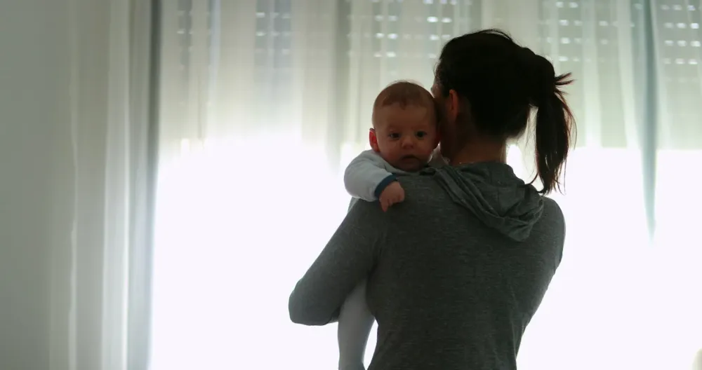 Спина матери, держащей новорождённого ребёнка