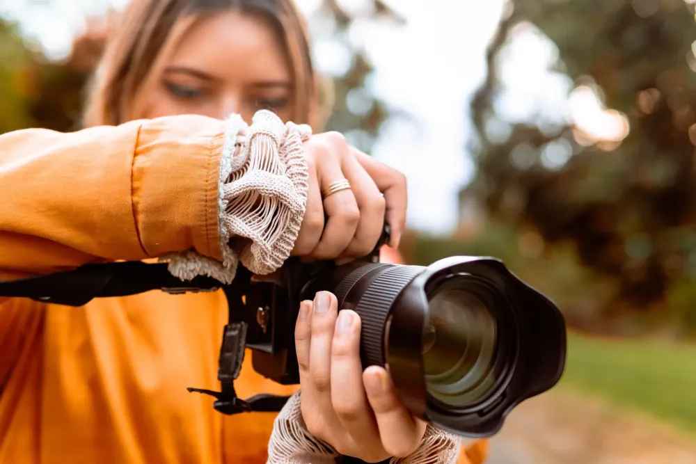Крупный план человека, использующего профессиональную камеру на открытом воздухе.